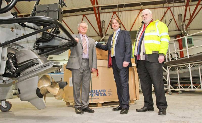 Bob Troop, chair and managing director James Troop & Co (in hi-vis jacket); Anthony Ward, engine sales executive James Troop & Co (grey suit); and Philip Hilbert, sales director MST (blue suit); seen with one of the new vessels at MST's construction facility and HQ, at Atlantic Way, Liverpool. (Photo: James Troop)